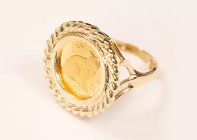 10 Karat Yellow Gold Ram Ring featuring a coin centerpiece with an embossed horse design, set against a white background.