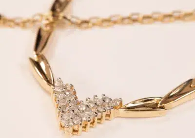 14K YG Diamonds & Peach Tourmaline Ring with a diamond-studded chevron pendant on a beige background.