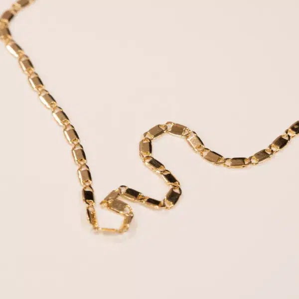 Gold chain with interlocking links on a plain beige background, featuring a 14K YG Diamonds & Peach Tourmaline Ring clasp.