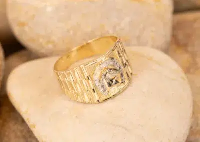 14K YG Diamonds & Peach Tourmaline Ring displaying a masonic symbol, resting on a smooth, peach tourmaline stone.