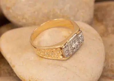 14K YG Diamonds & Peach Tourmaline ring with diamonds set on a beige stone surface.