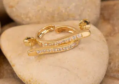 A 14K YG Diamonds & Peach Tourmaline Ring with embedded diamonds resting on a smooth, beige stone.